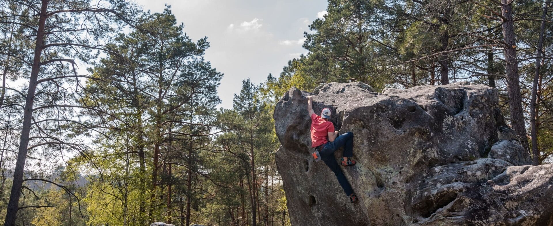 Mann klettert am Felsen im Fontainebleau.