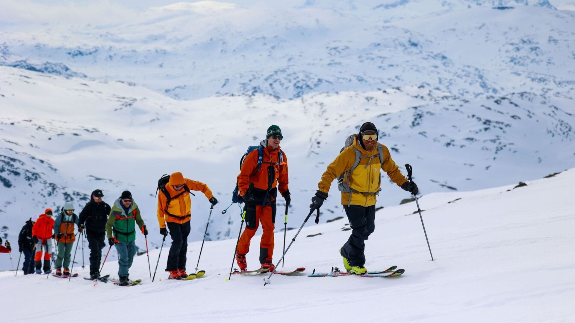 Eine Schlange an Menschen geht mit Skiern an den Füßen einen Berg hoch