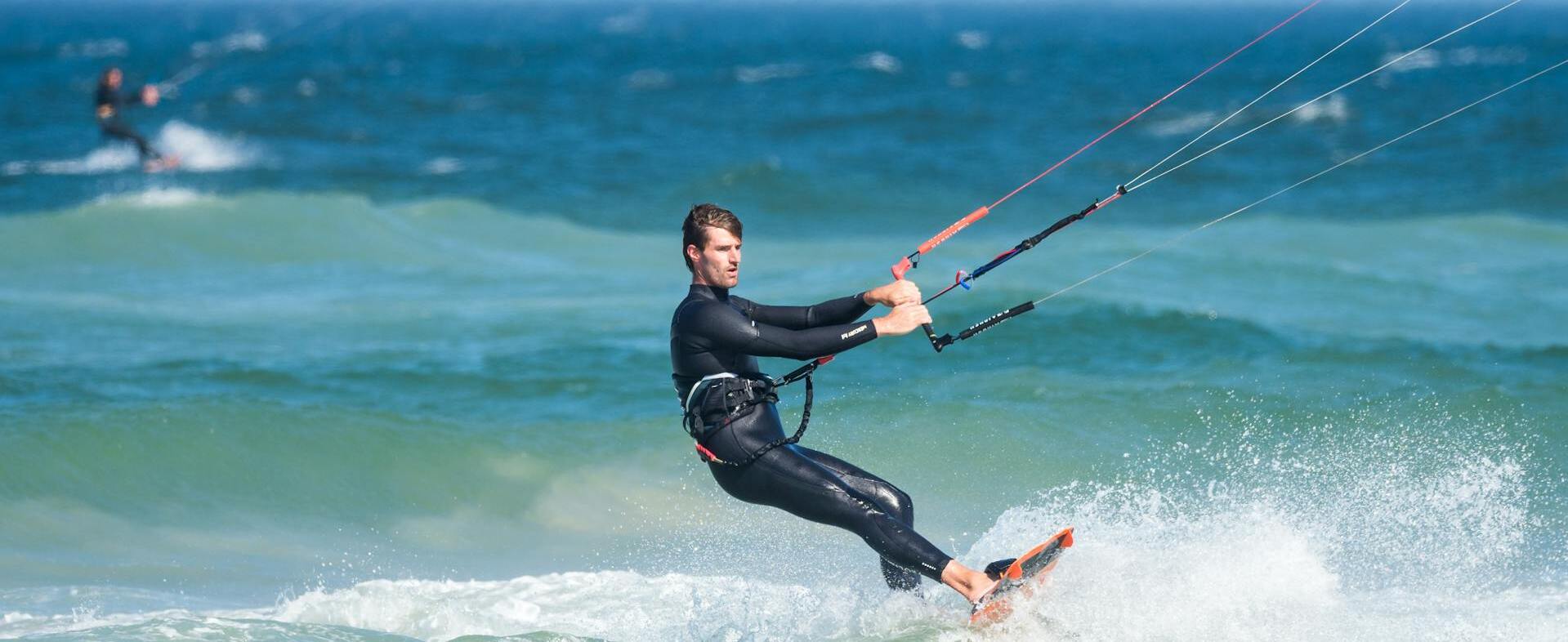 Mann mit Neoprenanzug beim Kitesurfen