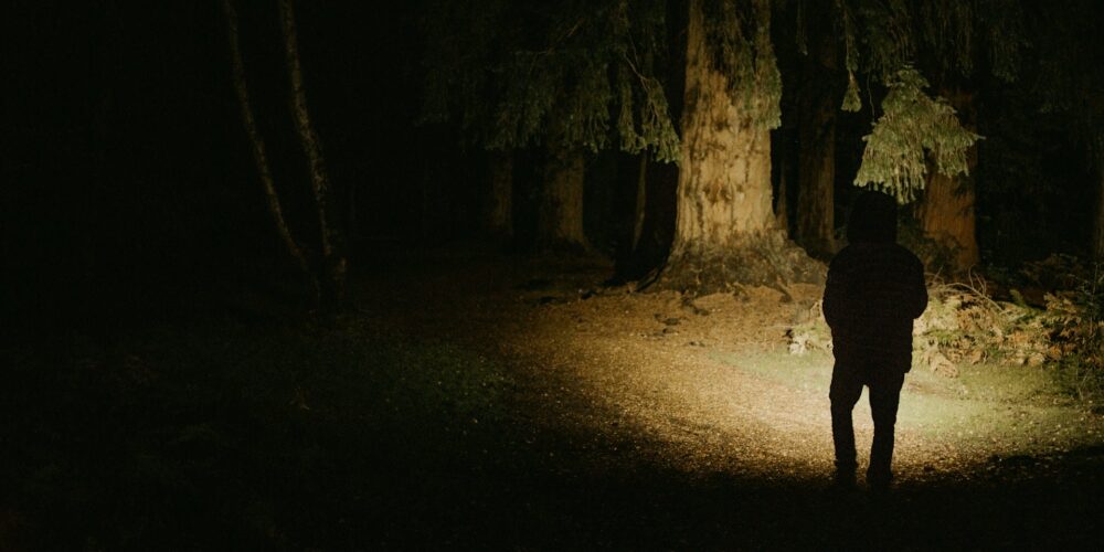 Person mit Stirnlampe im Wald